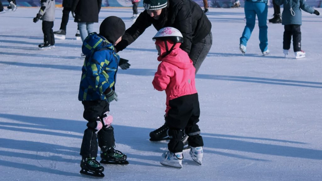 Two happy children ice skating with an adult