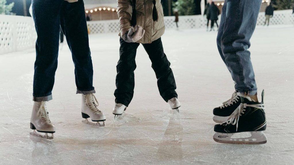 Three people making a stop while ice skating