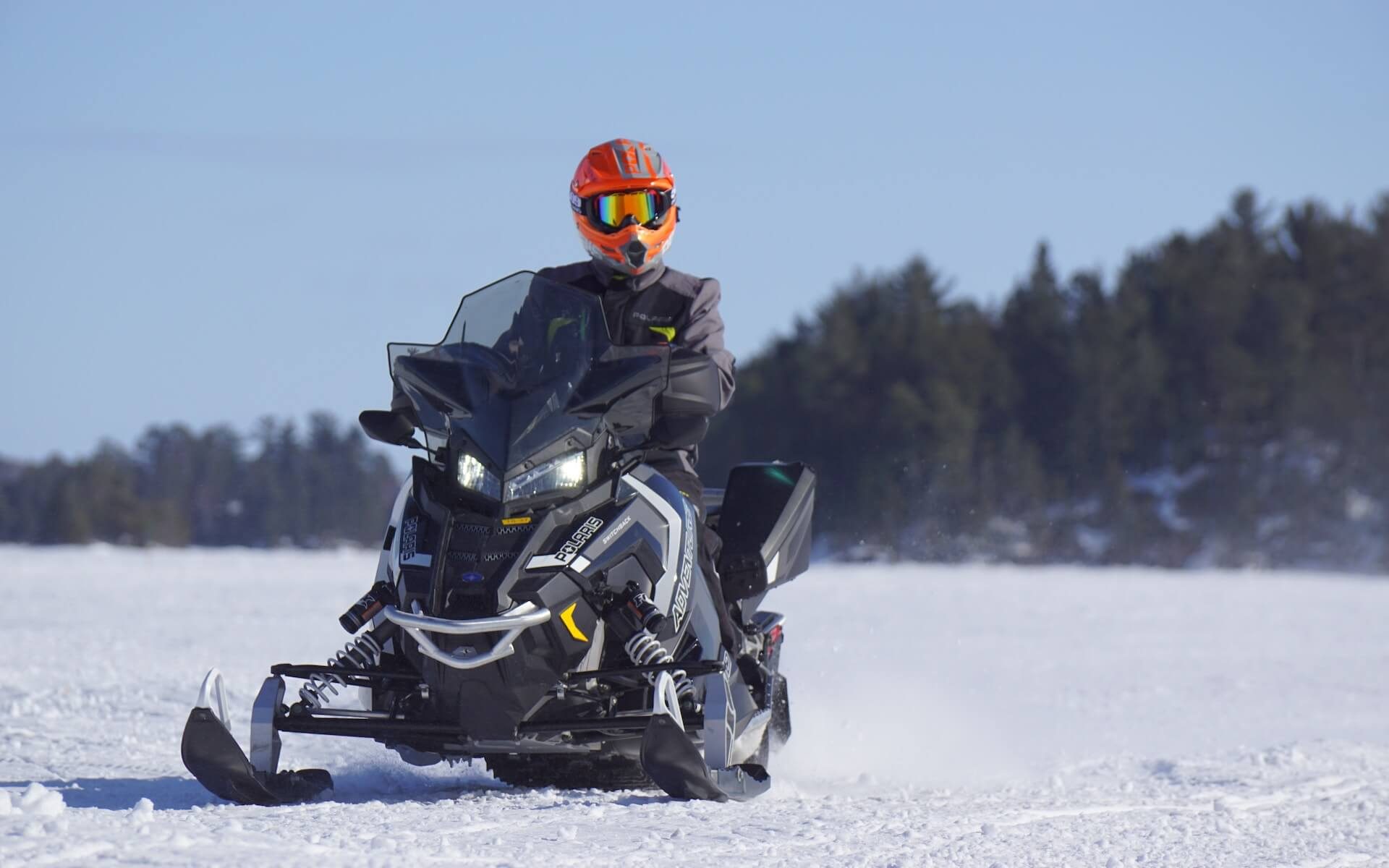 Person riding a snowmobile in a snowy terrain.